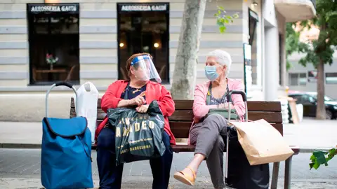 Dos señoras charlan sentadas en un banco del barcelonés barrio de la Sagrada Familia Dos señoras charlan sentadas en un banco del barcelonés barrio de la Sagrada Familia