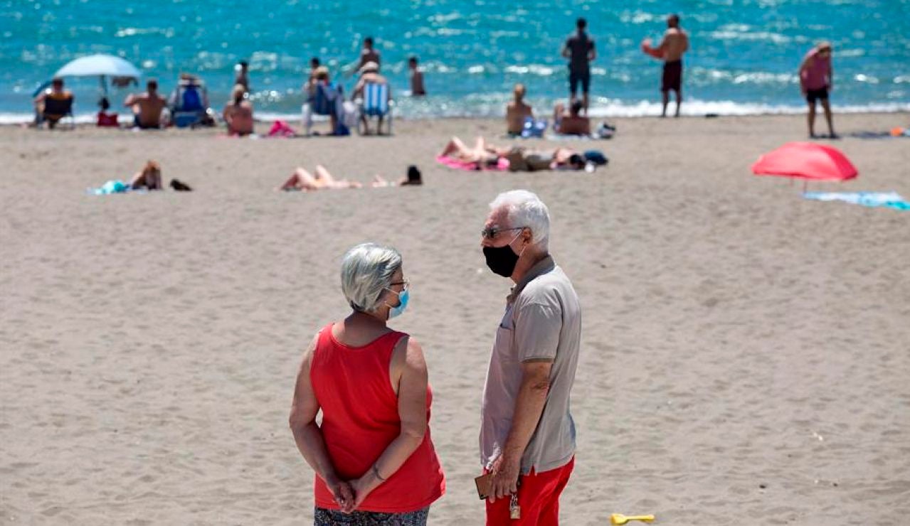 Personas con mascarilla en una playa