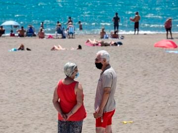 Personas con mascarilla en una playa