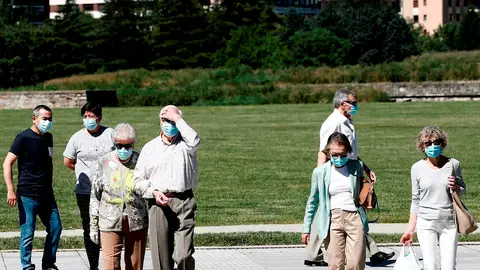 Un grupo de personas con mascarilla pasean por un parque Un grupo de personas con mascarilla pasean por un parque