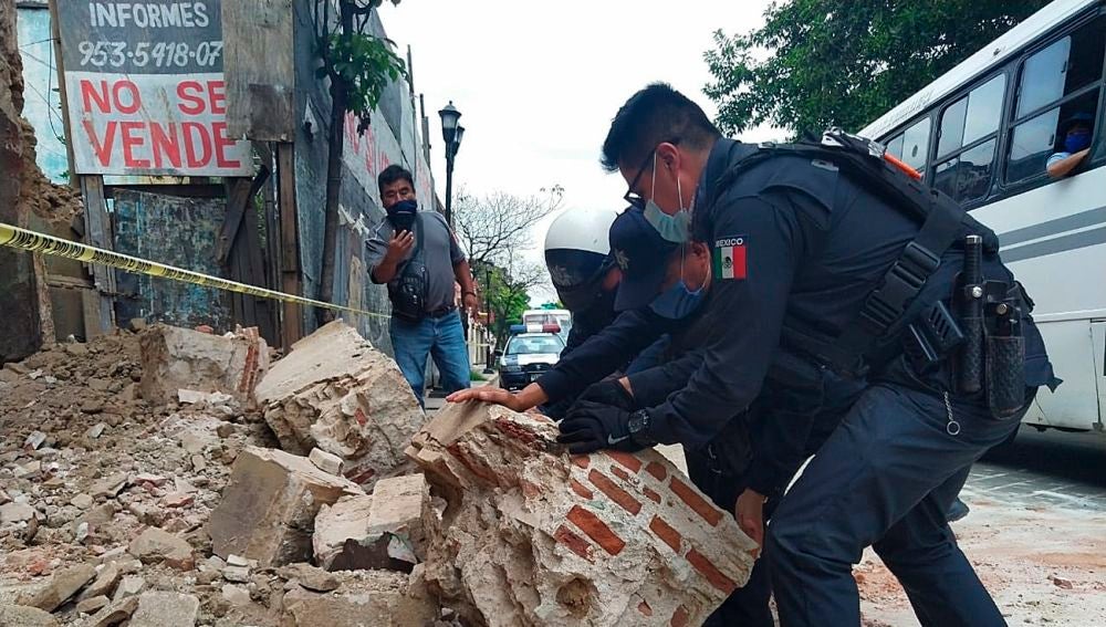 Policías y agentes de protección civil retiran escombros de una fachada derruida en Oxaca