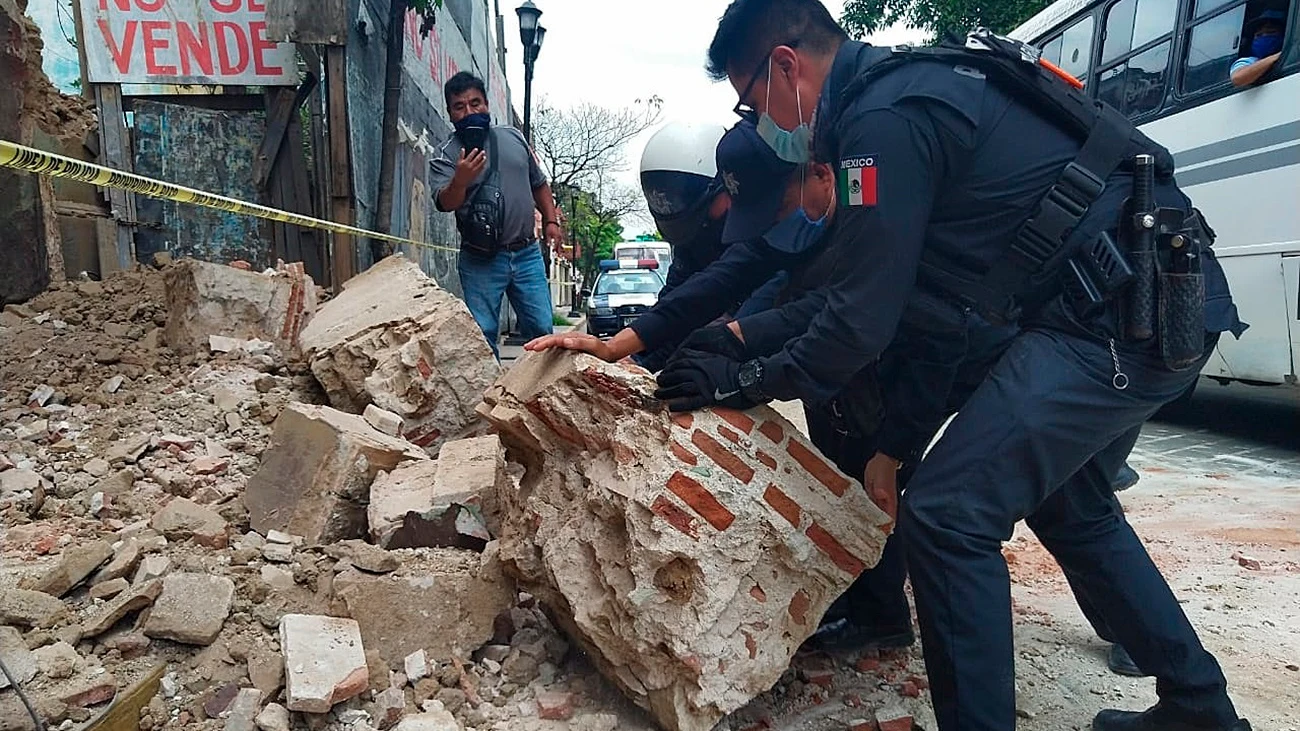 Polic&iacute;as y agentes de protecci&oacute;n civil retiran escombros de una fachada derruida en Oxaca