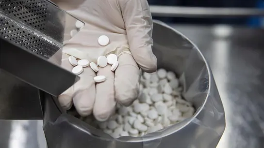 Un trabajador sostiene pastillas de un medicamento Un trabajador sostiene pastillas de un medicamento