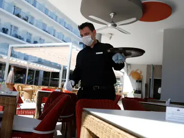 Un camarero trabajando mientras usa mascarilla facial contra el coronavirus Un camarero trabajando mientras usa mascarilla facial contra el coronavirus