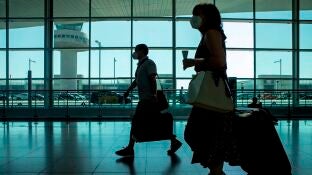 Viajeros con mascarillas caminan por el aeropuerto de El Prat