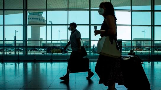 Viajeros con mascarillas caminan por el aeropuerto de El Prat