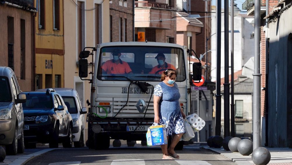  Una mujer pasa por delante de un camión que realiza tareas de desinfección por las calles de Íscar