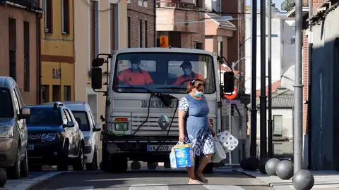 Una mujer pasa por delante de un camión que realiza tareas de desinfección por las calles de Íscar Una mujer pasa por delante de un camión que realiza tareas de desinfección por las calles de Íscar