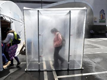 Personas pasan por una cabina de desinfección de coronavirus