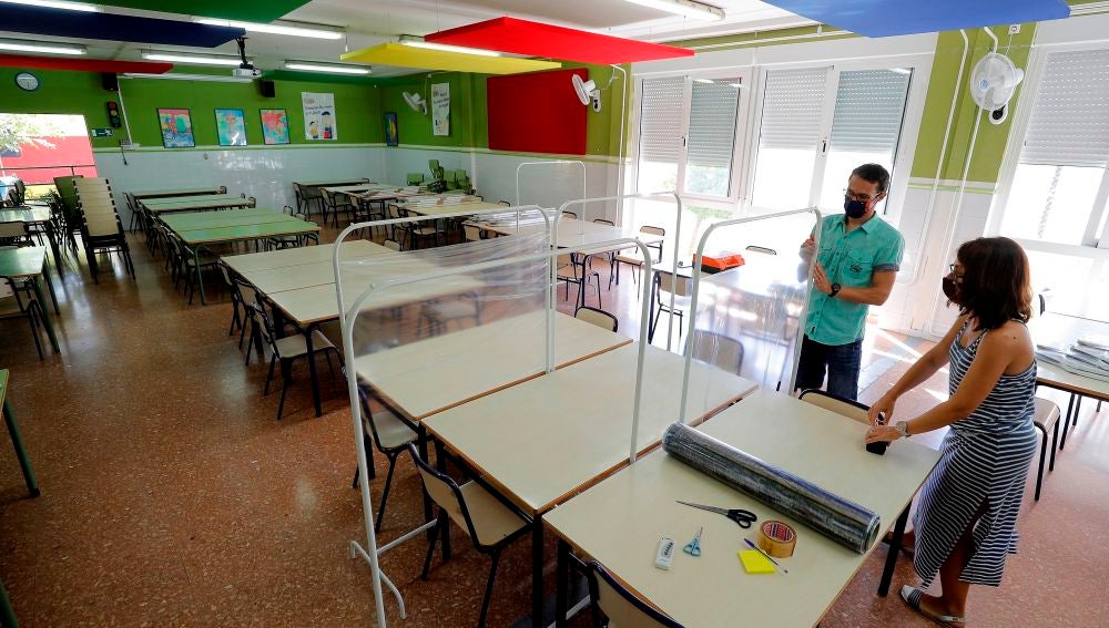 Dos docentes colocan los separadores en el comedor de un colegio