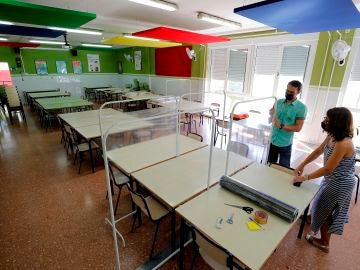 Dos docentes colocan los separadores en el comedor de un colegio