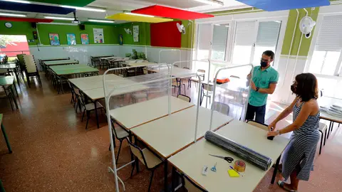 Dos docentes colocan los separadores en el comedor de un colegio Vuelta al cole