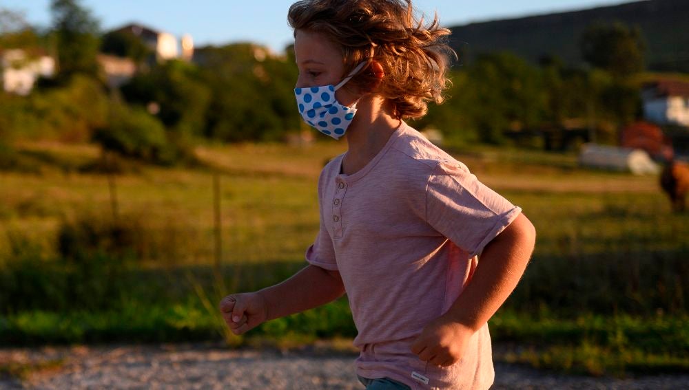 Un niño con mascarilla juega en la calle