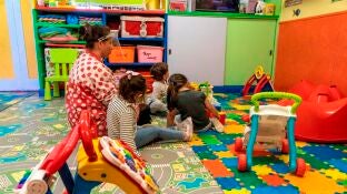 Una maestra con una pantalla protectora en un aula de Infantil con varios ni&ntilde;os