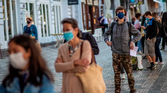 Una cola de gente con mascarillas en una calle de Italia Una cola de gente con mascarillas en una calle de Italia