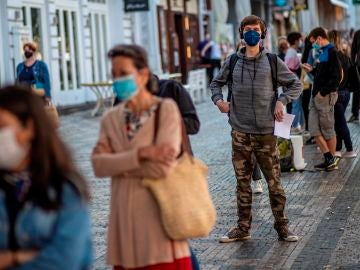 Una cola de gente con mascarillas en una calle de Italia