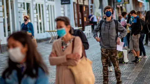 Una cola de gente con mascarillas en una calle de Italia Una cola de gente con mascarillas en una calle de Italia