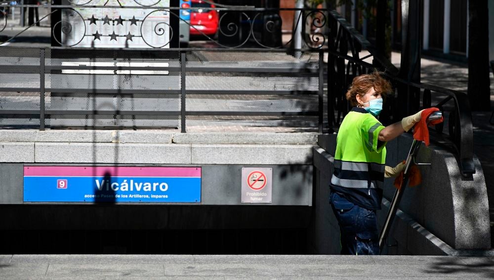 Una operaria limpia la barandilla de acceso del metro del barrio madrileño de Vicálvaro