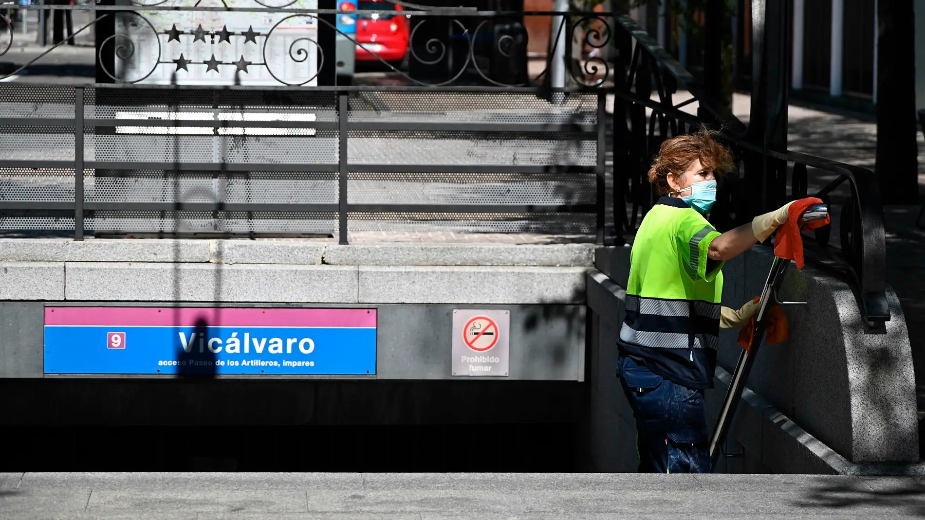 Una operaria limpia la barandilla de acceso del metro del barrio madrileño de Vicálvaro