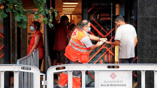 Un voluntario de la Cruz Roja atiende a un vecino del barrio del Remei de Vic (Barcelona).
