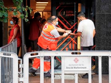 Un voluntario de la Cruz Roja atiende a un vecino del barrio del Remei de Vic (Barcelona).