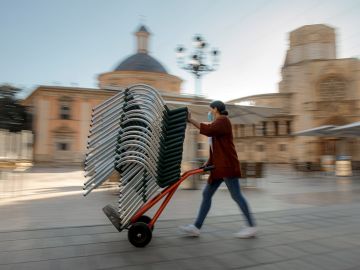 Una persona monta la terraza de un bar de una céntrica plaza de Valencia