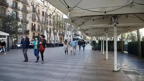 Varias personas pasean por las terrazas de las Ramblas Varias personas pasean por las terrazas de las Ramblas
