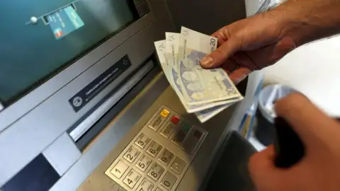 Una mujer saca dinero de un banco Una mujer saca dinero de un banco