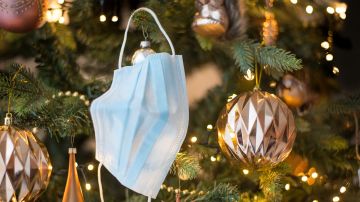 Una mascarilla colgada de un árbol de Navidad