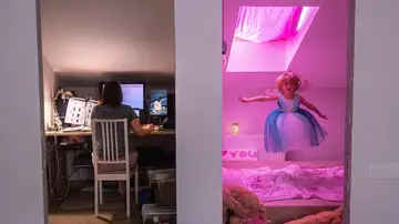 Mujer teletrabajando y niña jugando en casa Mujer teletrabajando y niña jugando en casa