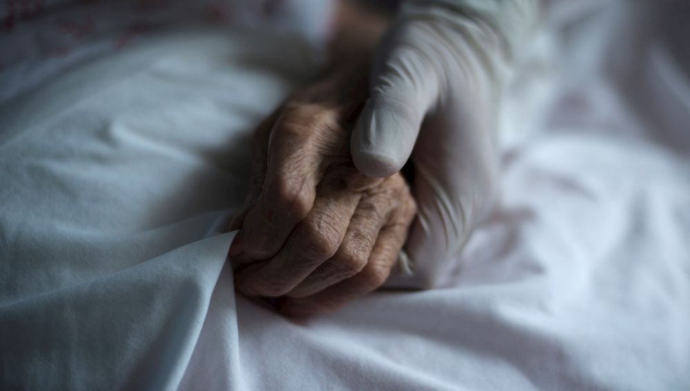 Mano de un sanitario junto a la de un paciente