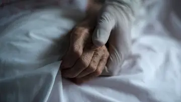 Mano de un sanitario junto a la de un paciente Mano de un sanitario junto a la de un paciente