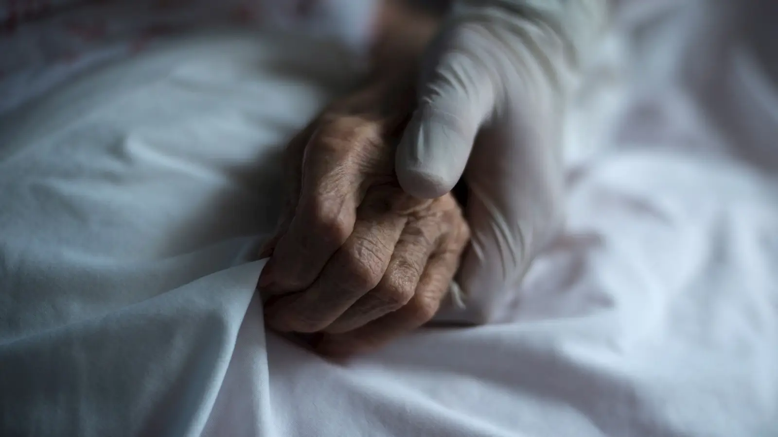 Mano de un sanitario junto a la de un paciente