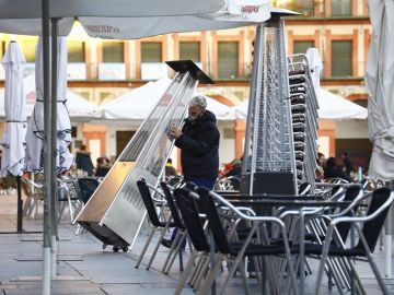 Un trabajador recoge el mobiliario de la terraza de un restaurante.