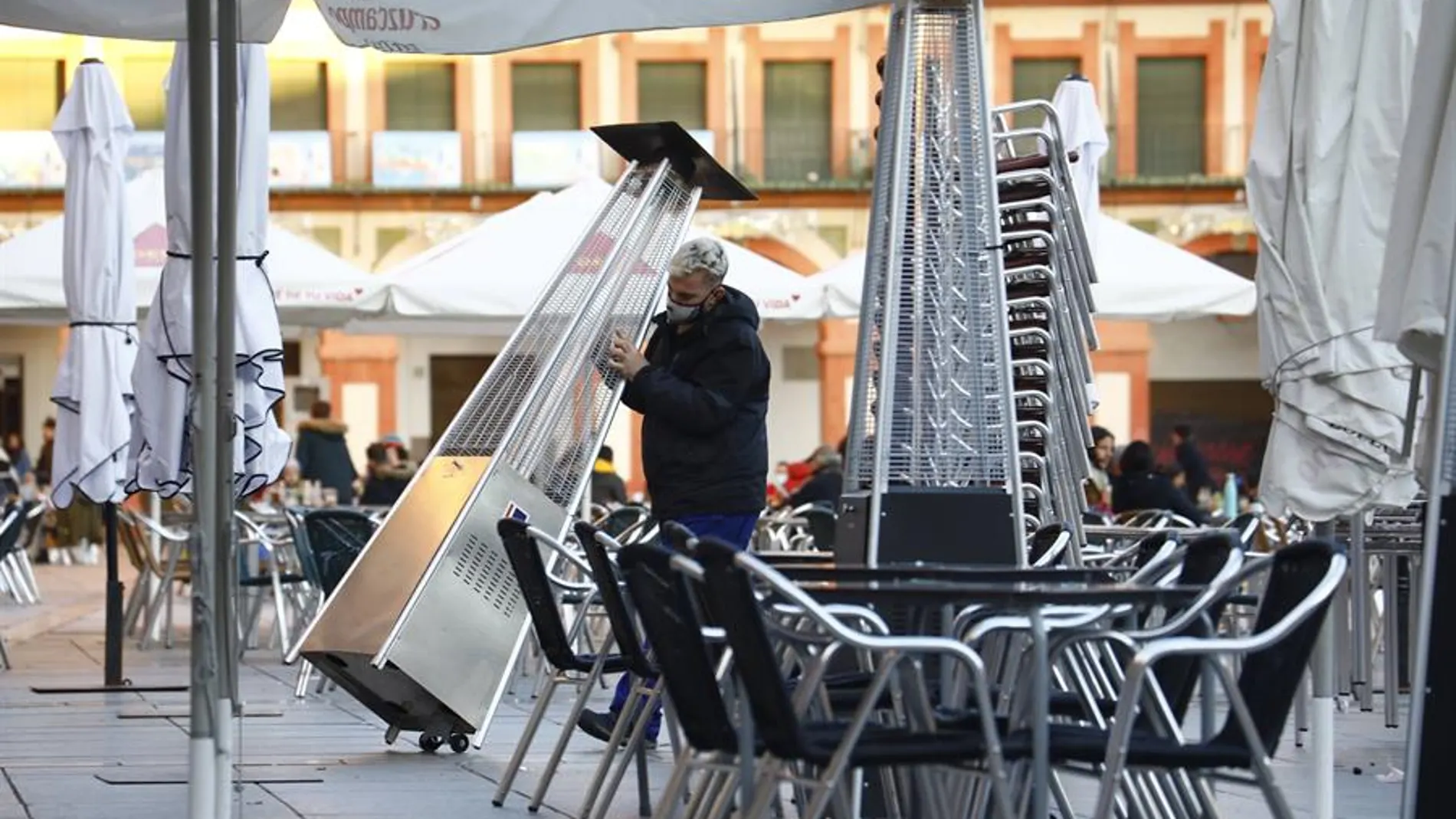 Un trabajador recoge el mobiliario de la terraza de un restaurante. Un trabajador recoge el mobiliario de la terraza de un restaurante.