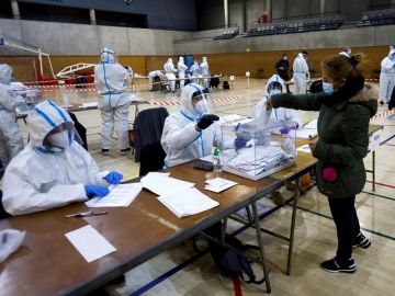  Varias personas equipadas con equipos de protección individual (EPI), trabajan en las mesas electorales del Polideportivo Municipal de la España Industrial de Barcelona