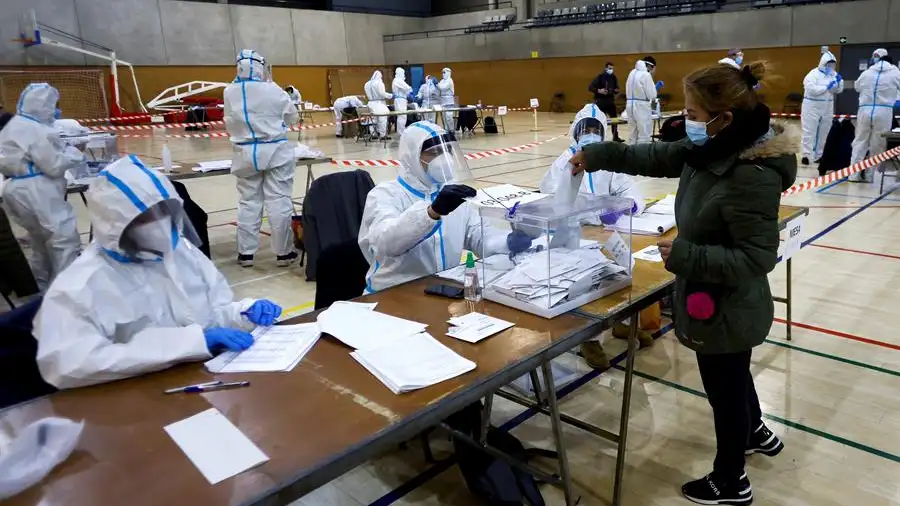  Varias personas equipadas con equipos de protecci&oacute;n individual (EPI), trabajan en las mesas electorales del Polideportivo Municipal de la Espa&ntilde;a Industrial de Barcelona