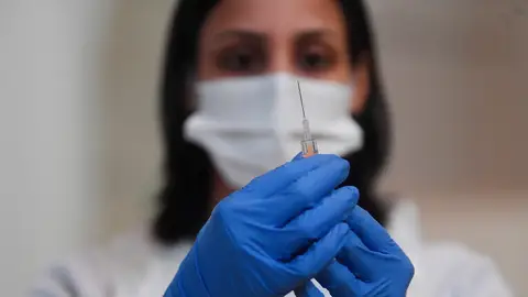 Una mujer sostiene una vacuna de Pfizer. Coronavirus