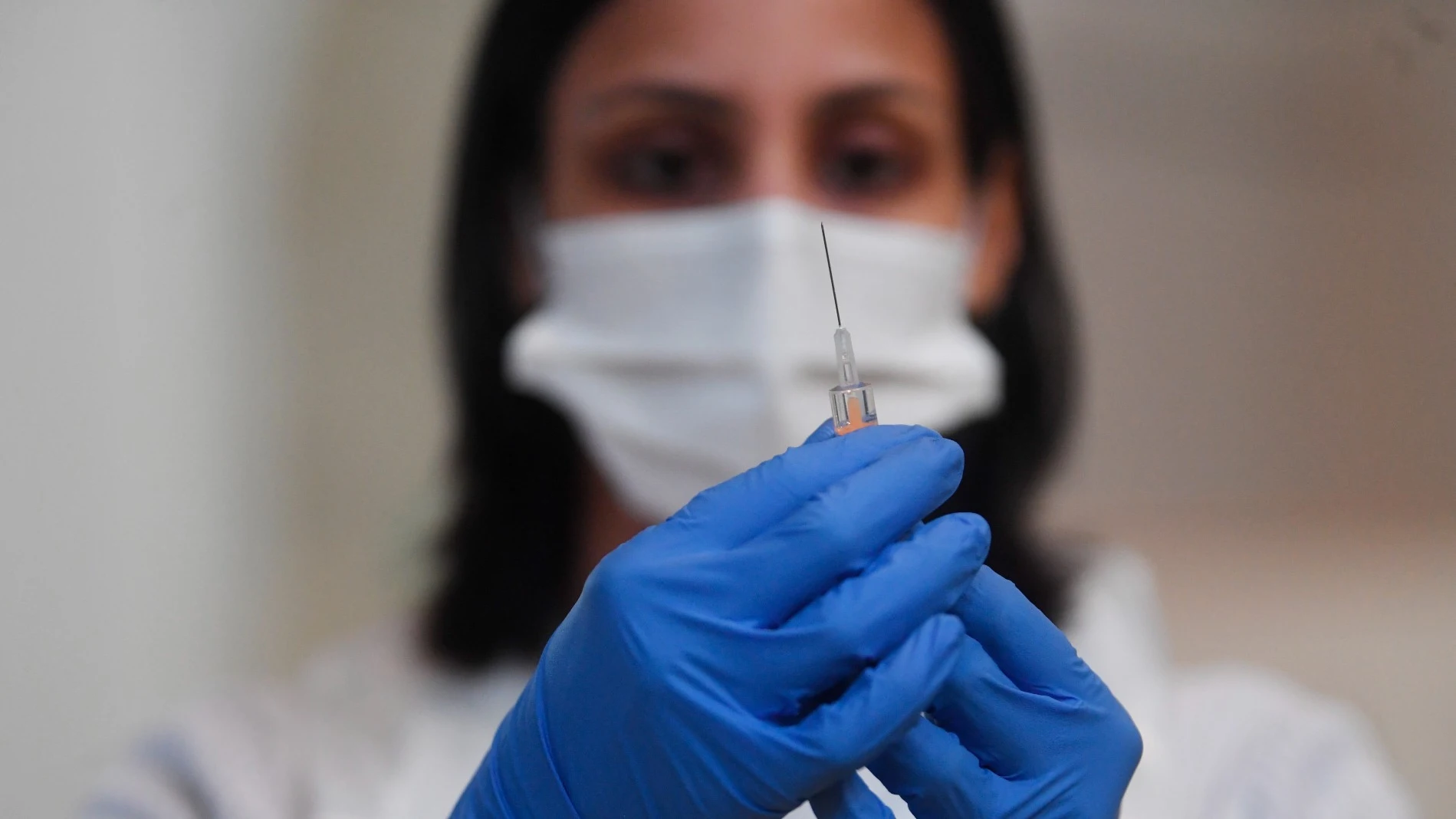 Una mujer sostiene una vacuna de Pfizer. Coronavirus