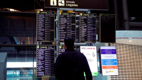 Un hombre observa un panel de llegadas en el Aeropuerto Adolfo Suárez Madrid Barajas. Coronavirus