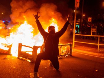 Un manifestante monta una barricada en Barcelona.