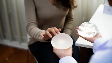 Un médico muestra tipos de implantes de pecho a una mujer. Prótesis mamarias