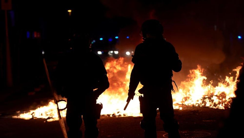 Agentes de los Mossos junto a una barricada en llamas en la Calle Aragó