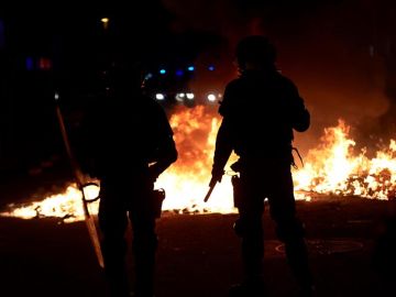 Agentes de los Mossos junto a una barricada en llamas en la Calle Aragó