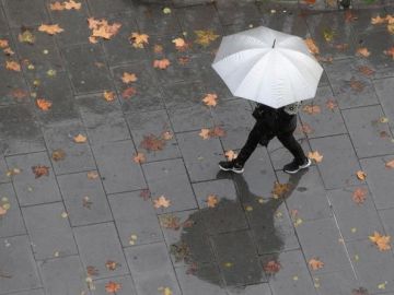 Imagen de archivo de una persona caminando bajo la lluvia