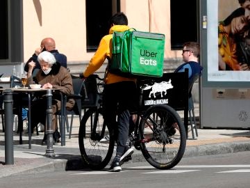 Un repartidor de Uber Eats aguarda junto a un establecimiento de hostelería en Madrid