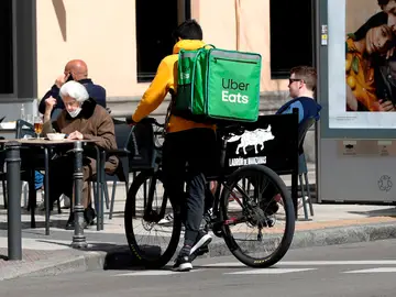 Un repartidor de Uber Eats aguarda junto a un establecimiento de hostelería en Madrid Un repartidor de Uber Eats aguarda junto a un establecimiento de hostelería en Madrid