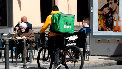 Un repartidor de Uber Eats aguarda junto a un establecimiento de hostelería en Madrid Un repartidor de Uber Eats aguarda junto a un establecimiento de hostelería en Madrid