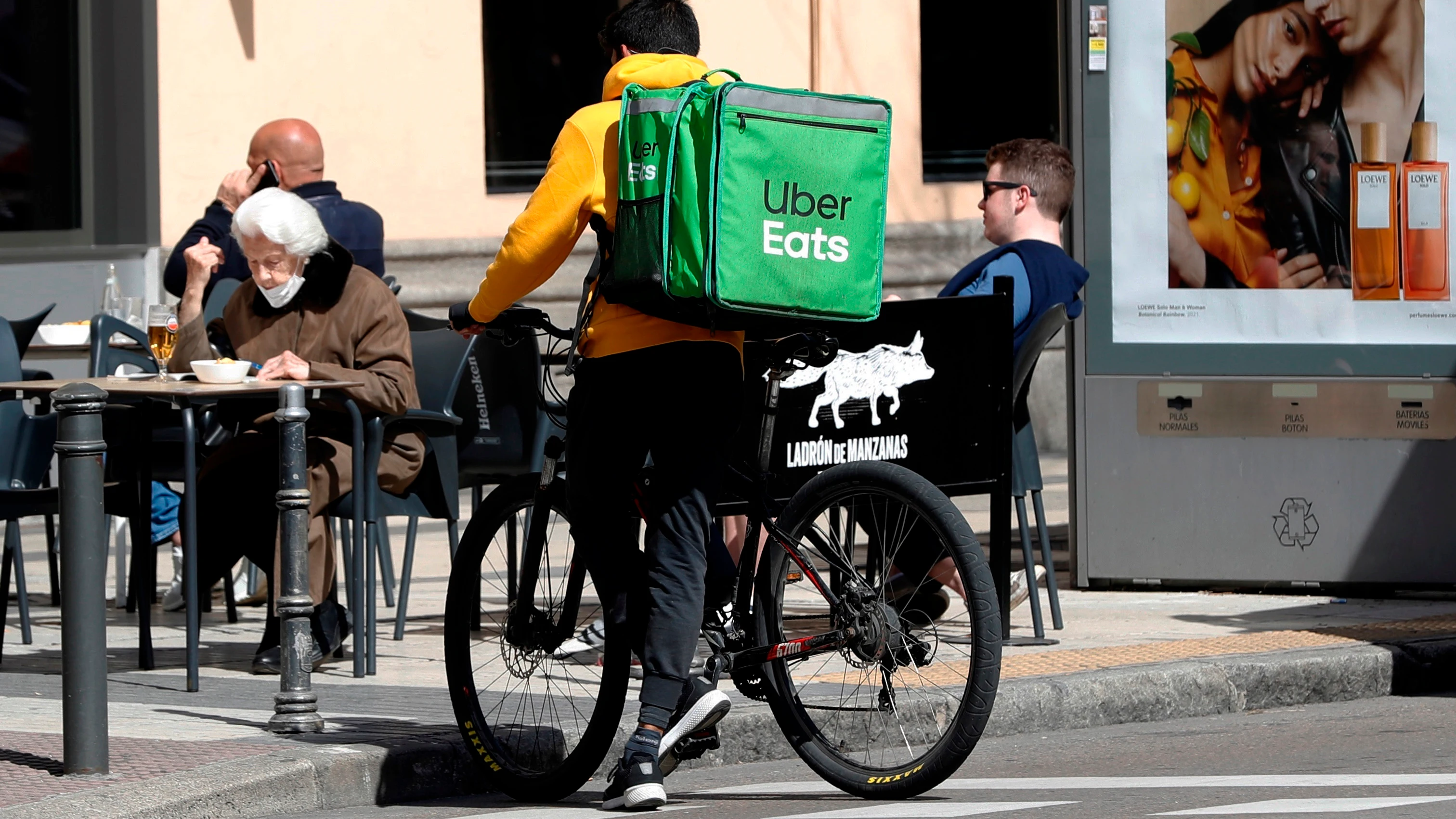 Un repartidor de Uber Eats aguarda junto a un establecimiento de hosteler&iacute;a en Madrid