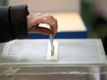 Una persona deposita su voto en una urna Una persona deposita su voto en una urna